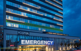 Emergency room entrance at modern hospital building in front of night sky.