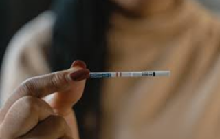 A woman holds a fentanyl test strip up.