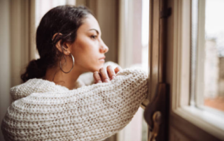 A woman looks out a window in contemplation.