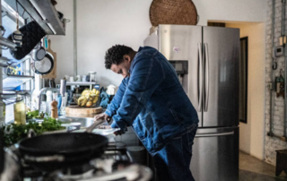 A man sulks, standing over a kitchen counter.